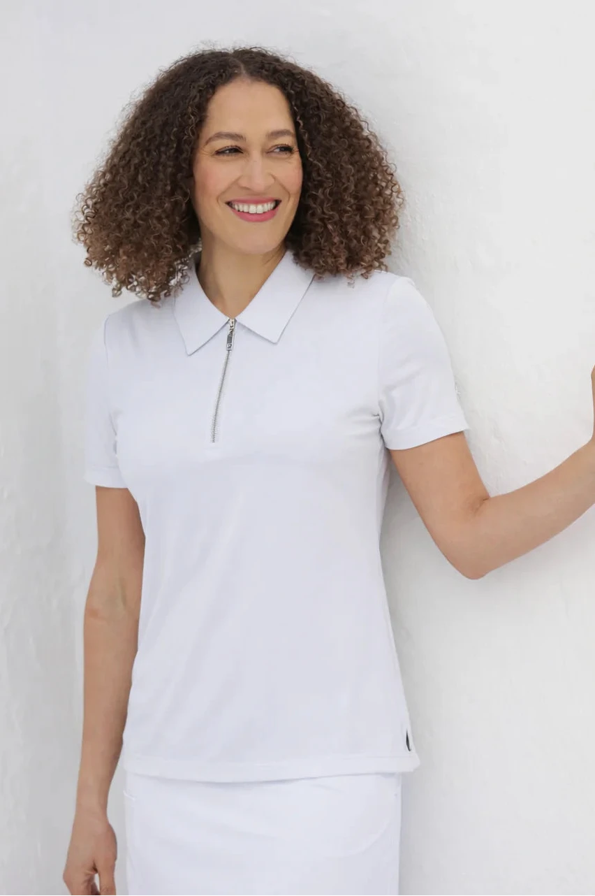 Woman wearing a white polo shirt against a plain background