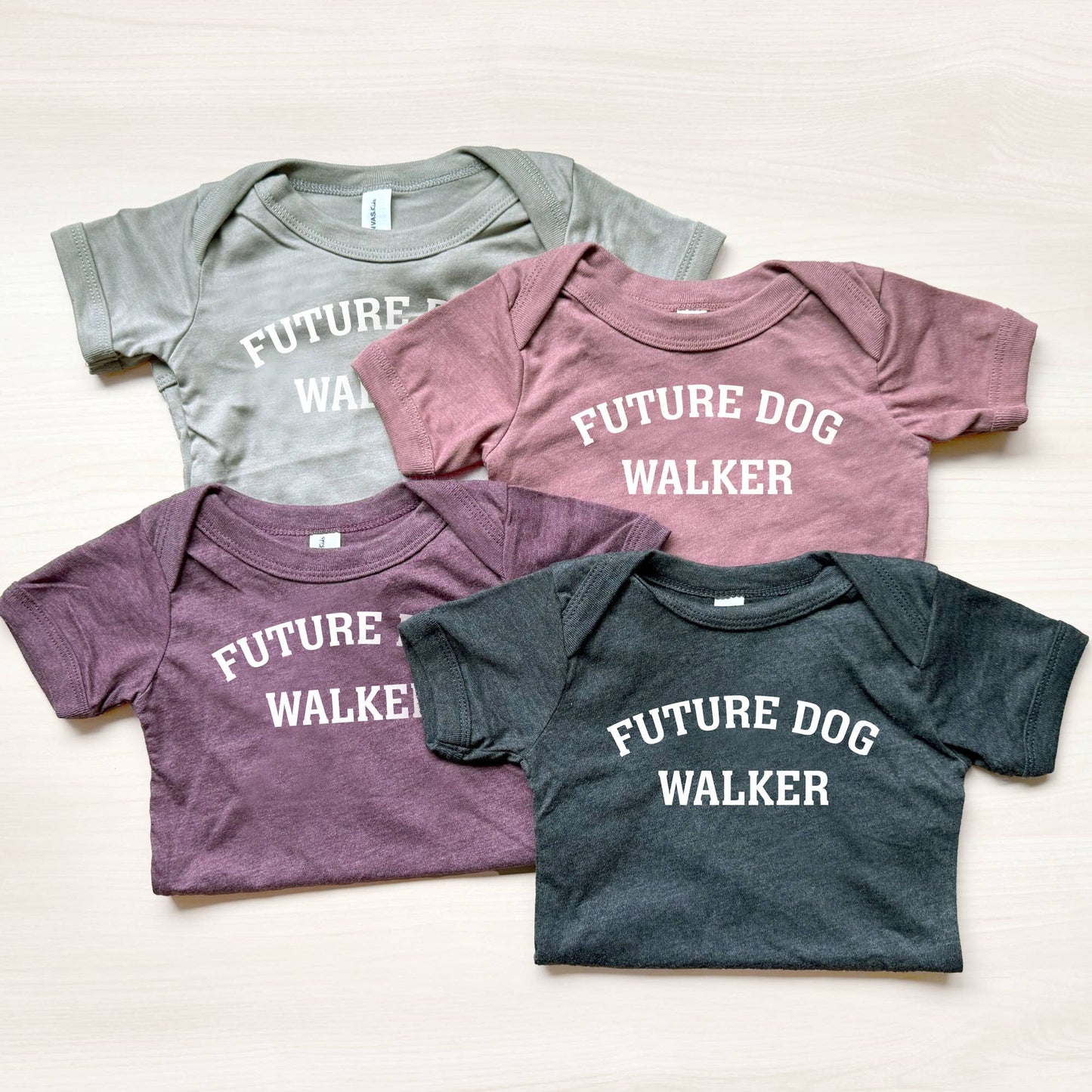 Four baby onesies with 'Future Dog Walker' text in different colors on a light background