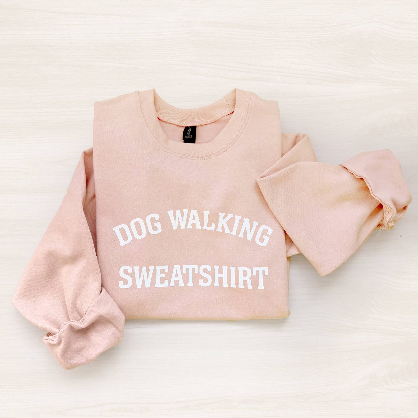 Pink sweatshirt with 'DOG WALKING SWEATSHIRT' text on a light background