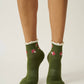 Green socks with red and white patterns worn by a person on a plain background