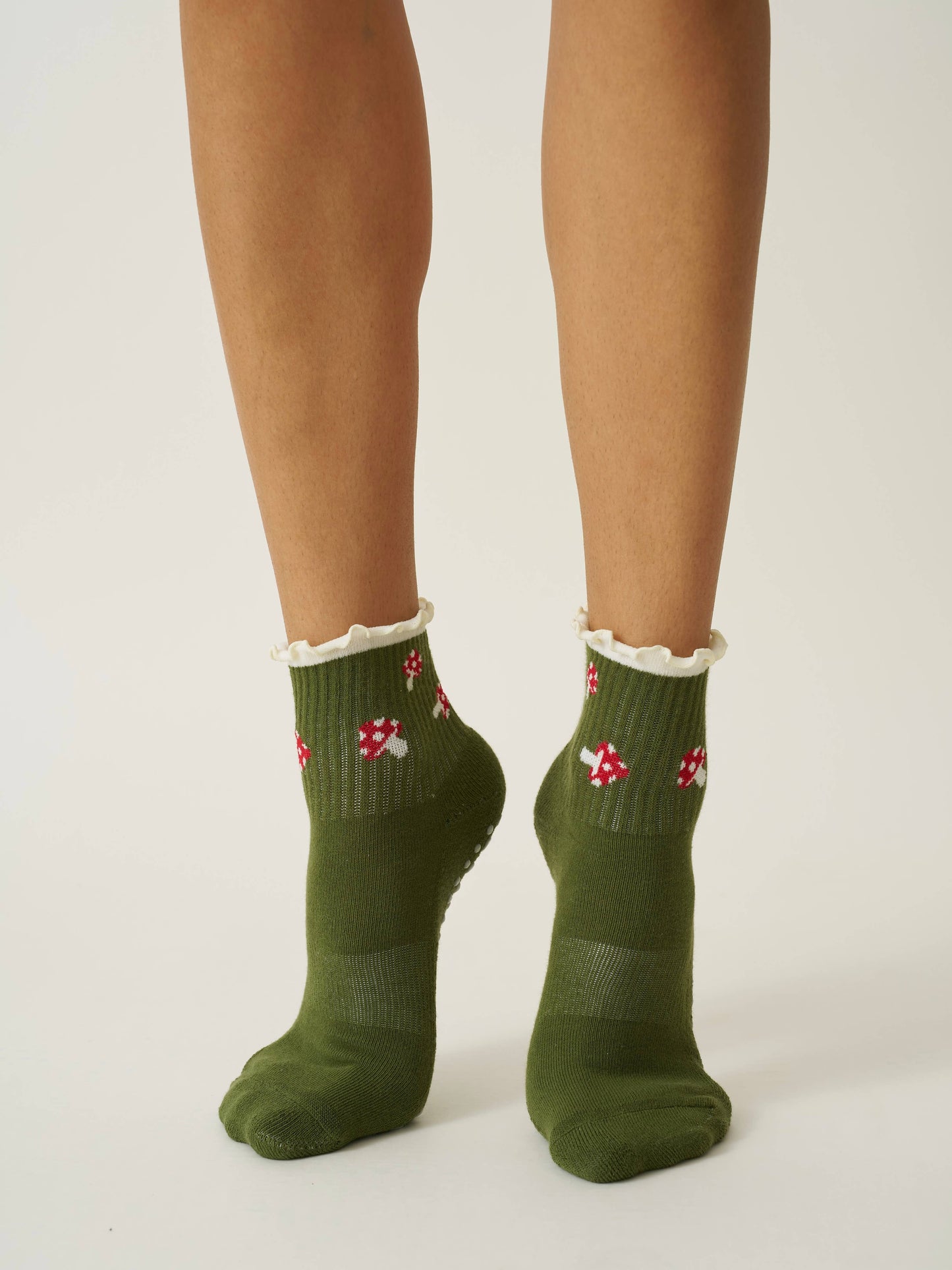 Green socks with red and white patterns worn by a person on a plain background