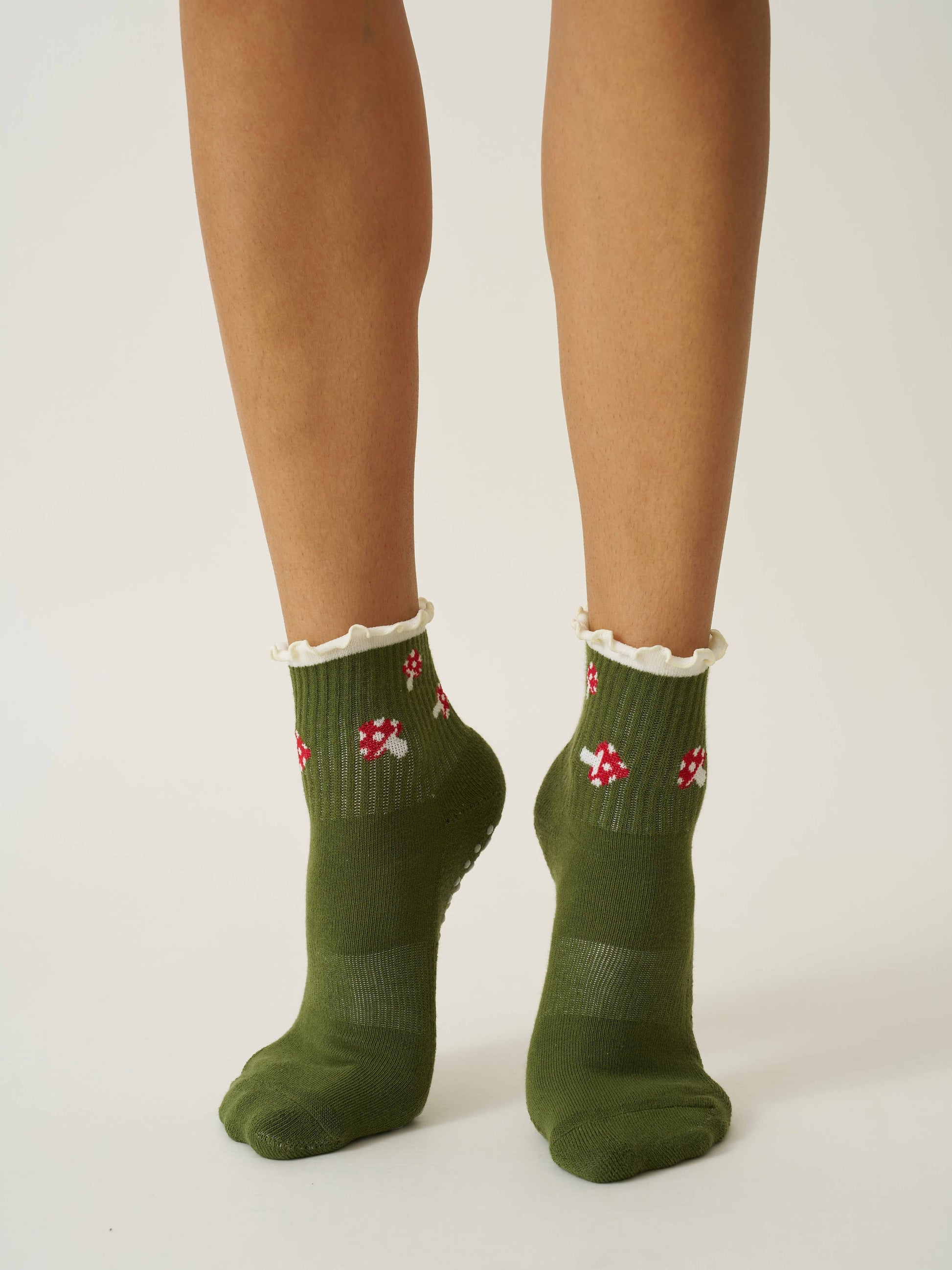 Green socks with red and white patterns worn by a person on a plain background